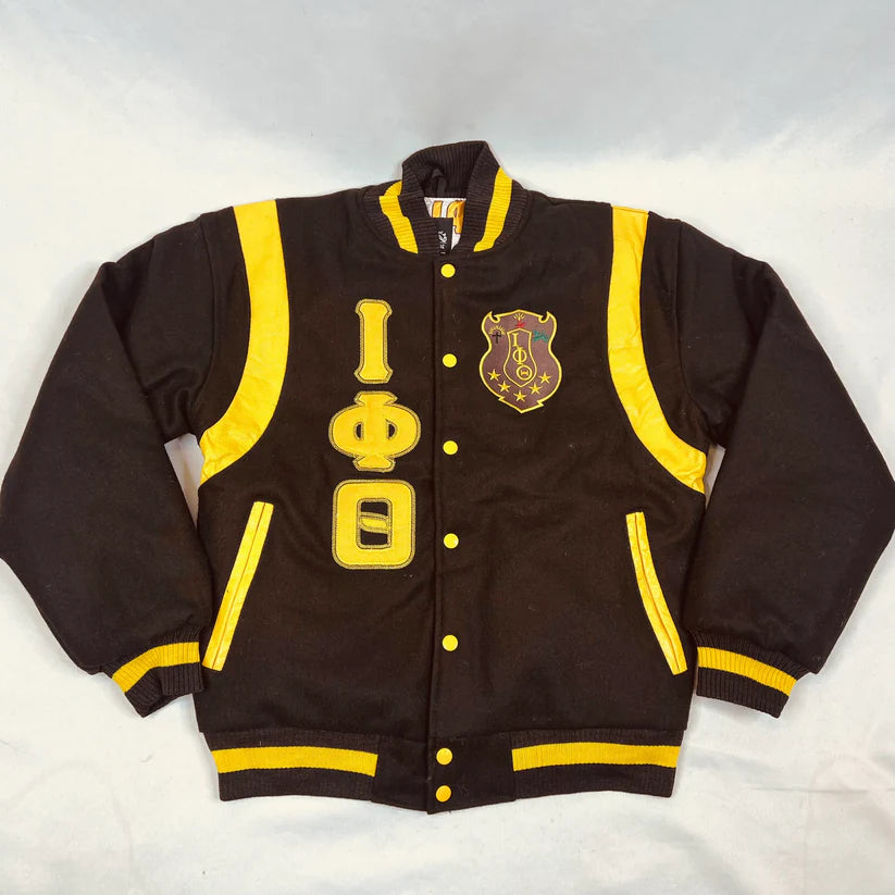 A close-up of the Iota Wool Letterman Jacket showing the luxurious texture of the dark chocolate brown 100% cashmere wool body contrasting with the premium leather detailing. Highlights the high-quality embroidered Iota Phi Theta (IOT) logo.